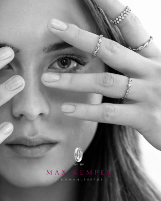 Frau hält Hand mit mehreren Ringen vor ihr Gesicht